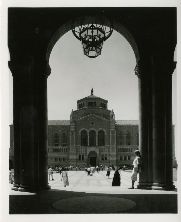 View of Powell Library through Royce Hall arches as students walk in quad