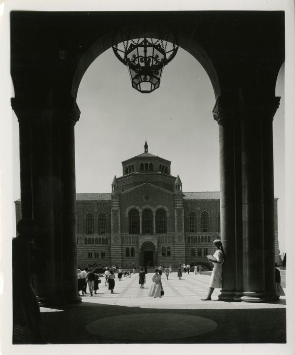 View of Powell Library through Royce Hall arches as students walk in quad