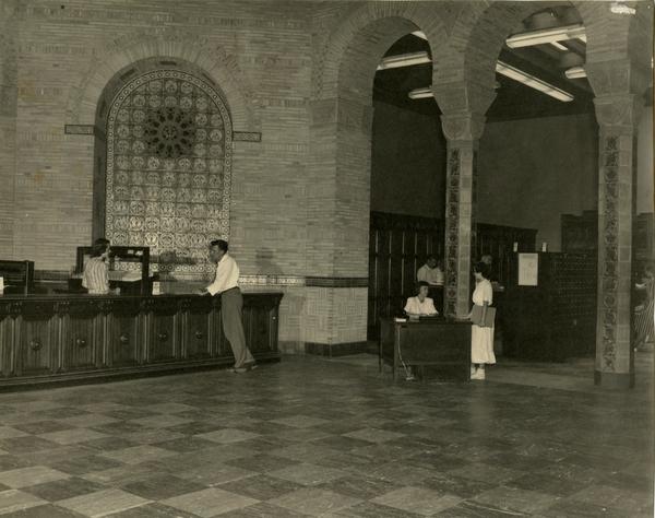 Library staff at Loan and Information desks assisting patrons at Powell Library, 1949