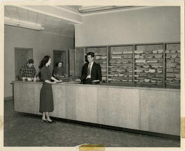 Library staff assisting a patron at the Periodicals reference desk