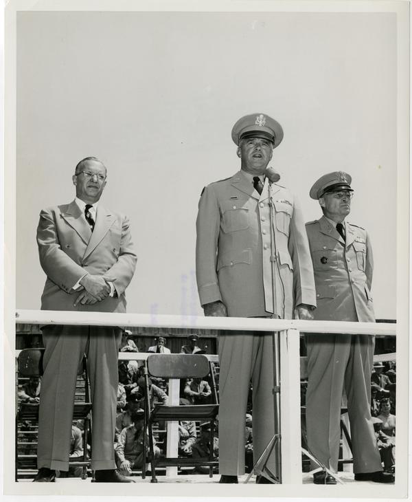 General William F. Dean addresses UCLA ROTC Cadet Regiment at Graduation parade while Chancellor Raymond Allen and Colonel Maxwell Thompson stand on either side, June 2, 1955