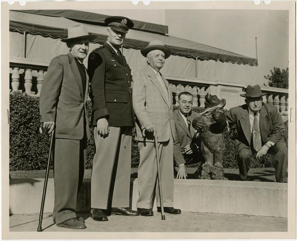 Photo of Roger J. Adams, General William F. Dean, William A. Baker, Harry W. Henry, and Joseph O. Morris Pasadena with Bruin mascot at Pasadena Civic Auditorium following the Kick-Off Luncheon, December 31, 1953