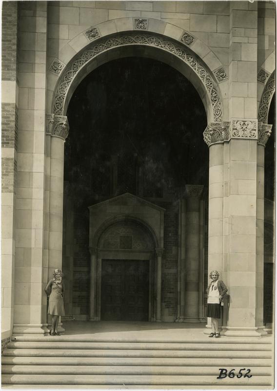 Two women standing underneath arcade of Royce Hall