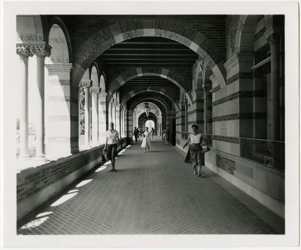 View of students walking down arcade of Royce Hall, ca. July 1958
