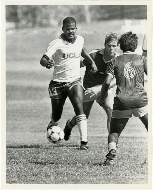 UCLA soccer player, Mark Clay, dribbling ball past opponents