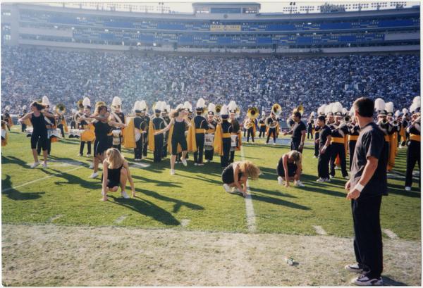 Spirit Squad performing at game with marching band in background, ca. November 1998