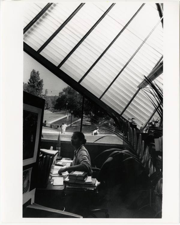 View of Library staff member at desk in Temporary Powell Library with Janss Steps visible in background