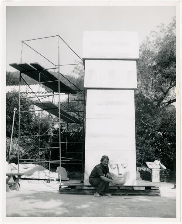 Anna Mahler sitting beside fifteen foot limestone column with clay model sketch before sculpting