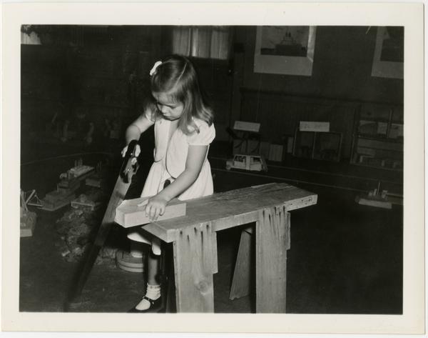 Child sawing piece of wood at Training School