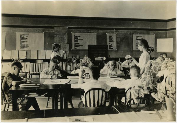 Children sitting at tables in classroom of Training School, ca. 1920