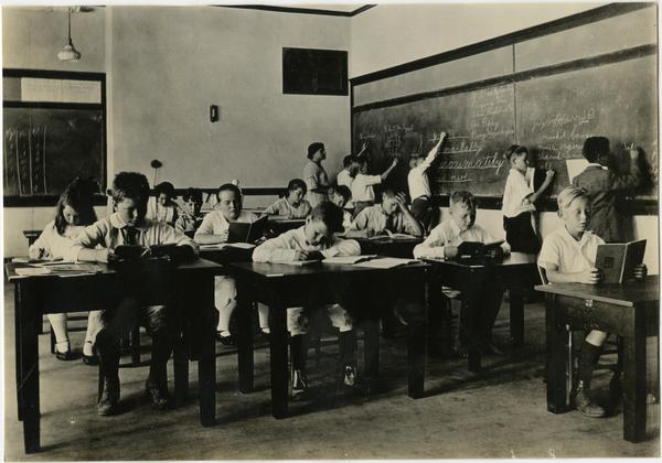 Children sitting at tables in classroom of Training School, ca. 1920