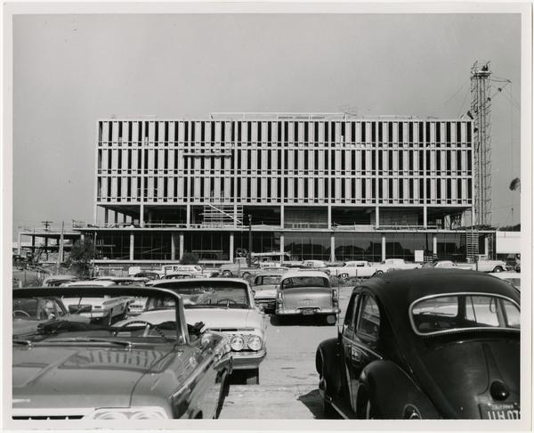 View of cars parked with construction of University Research Library in the background