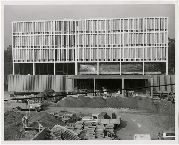 Frontal view of construction of the University Research Library with workers in the foreground