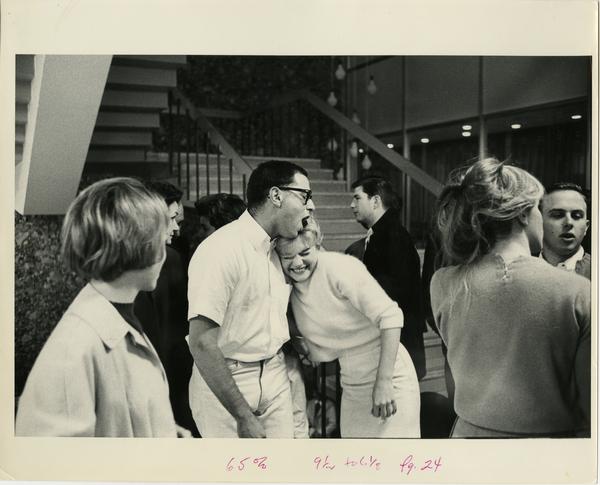 Students hugging beside a stair case, ca. 1964
