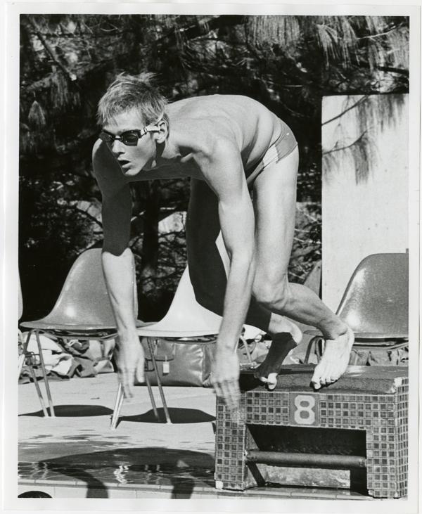 UCLA swim team member, Daniel Stephenson, jumping into pool from starting position, ca. 1979
