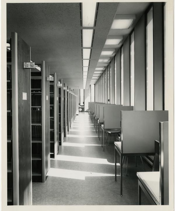 Desks lined up next to a stack in the University Research Library, ca. 1964