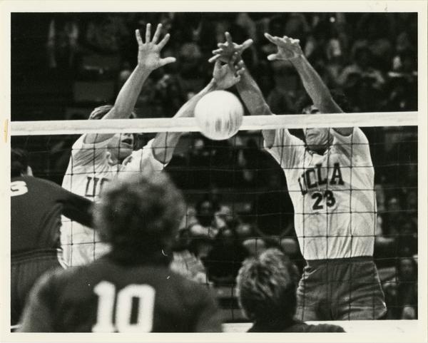 Two UCLA volleyball players attempting to block the ball during a game