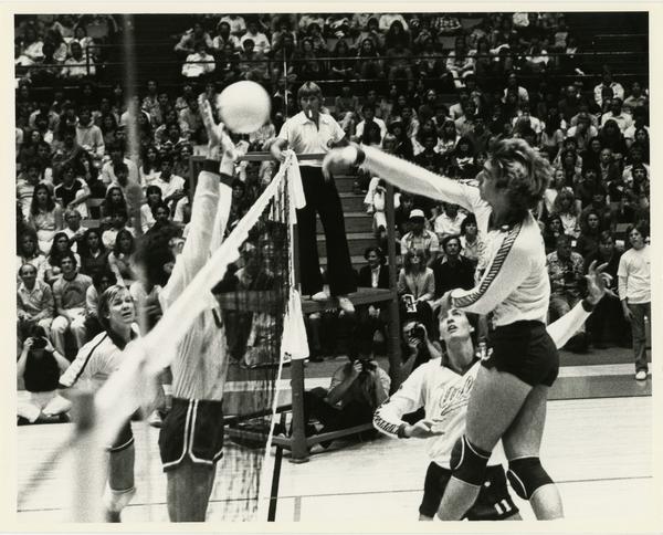 UCLA volleyball player spiking the ball over the net during a game