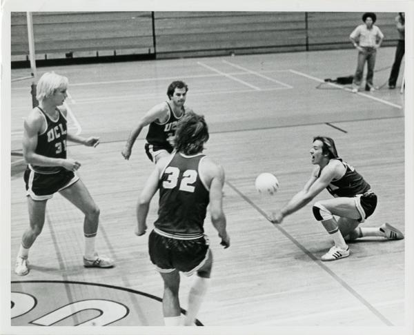 UCLA volleyball player hitting the ball as teammates look on during a game