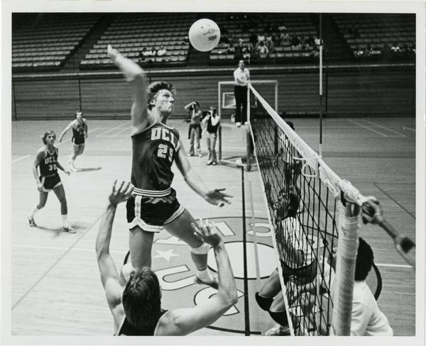 UCLA volleyball player about to spike the ball over the net during a game