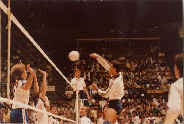 UCLA volleyball player after spiking the ball over the net during a game, 1983