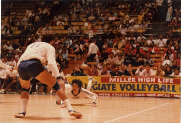 UCLA volleyball player diving for the ball during a game, 1983