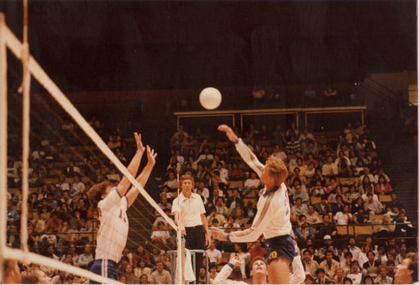 UCLA volleyball player about to hit the ball during a game as opposing teammembers attempt to block, 1983