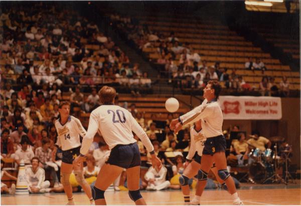 UCLA volleyball player hitting the ball surrounded by teammates during game, 1983