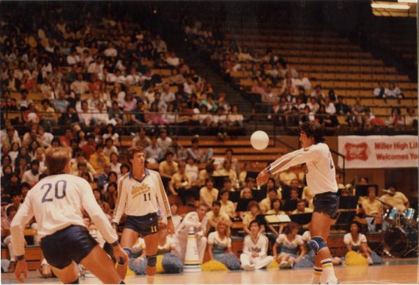 UCLA volleyball player hitting the ball surrounded by teammates during game, 1983