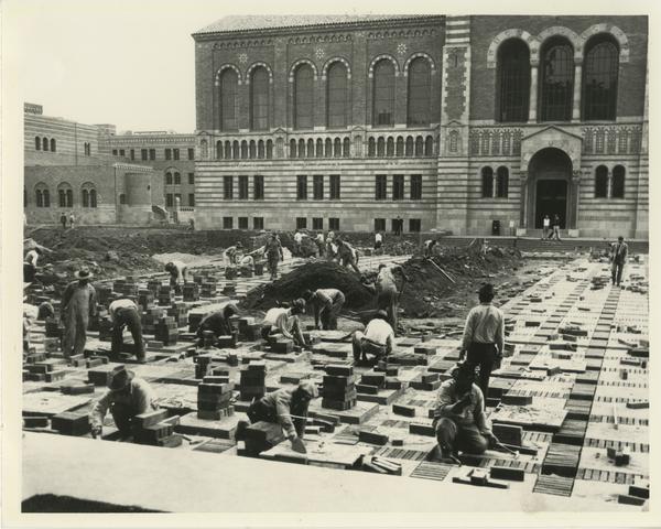 Construction workers paving Dickson Court with Powell Library in the background, ca. 1928
