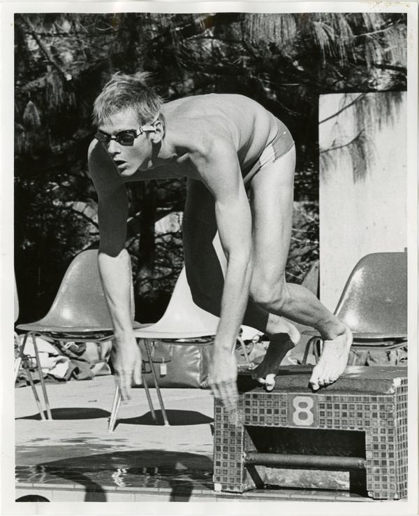 Team captain of the swim team, Dan Stephenson, pushes off starting block during event, 1979