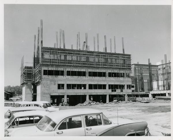 Medical Center during construction with cars parked nearby, 1959
