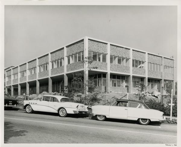 A completed UCLA medical center with cars parked in the street out front, 1962