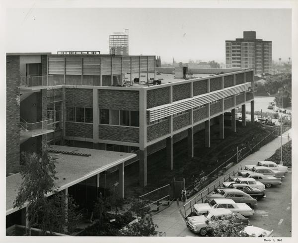 A completed UCLA medical center with parks parked in the street out front, 1962