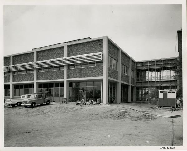 Part of the UCLA medical center close to completion, still standing on dirt and with work trucks parked around it, 1962