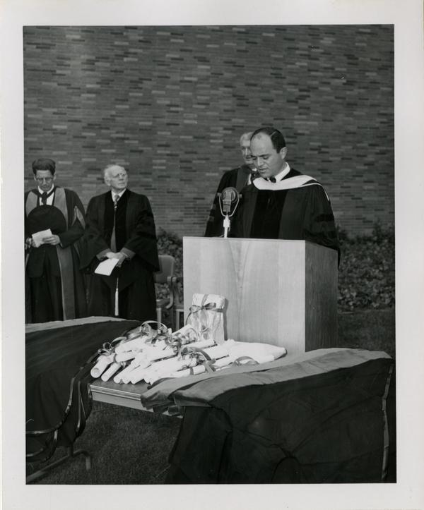 Member of the academic procession addresses the crowd at the graduation, 1956