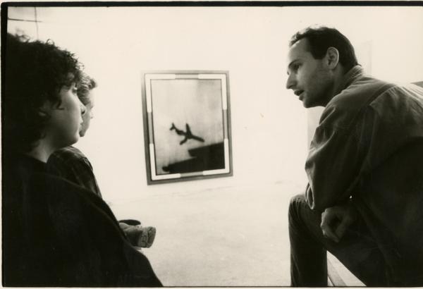 Three people discussing artwork at center