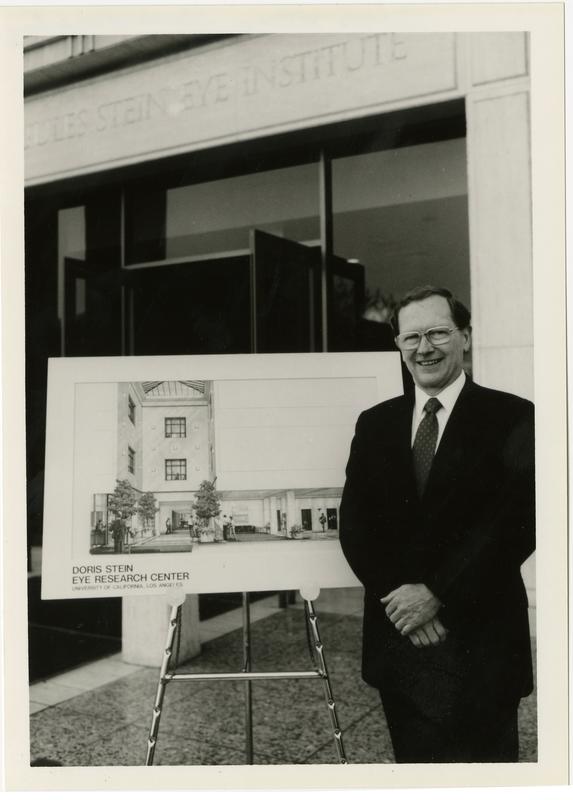 Man stands in front of partial rendering of Doris Stein Eye Research Center building