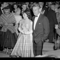 Actors Natalie Wood and Tab Hunter arriving at the 28th Academy Awards with gossip writer Louella Parsons in background, 1956
