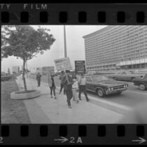 Protesters holding signs in front of the Century Plaza Hotel before Pres. Johnson's visit. 1967.