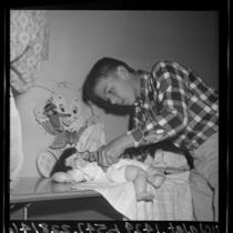 5th grade boy pinning diaper on baby doll in family life class at Steele Elementary School, Torrance, Calif., 1965