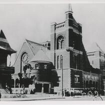 People and automobiles standing outside the First Baptist Church