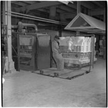 Employee pulls a cart of ceramic toilets at the Universal-Rundle factory, Redlands, 1940s