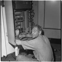 Man fixing a machine during the Army-Navy maneuvers that took place off the coast of Southern California in late 1946