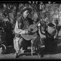 Eugene R. Plummer with guitar and Indian artifacts, Hollywood, 1927