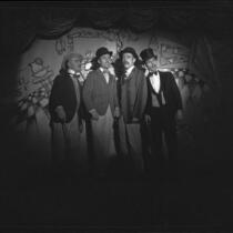 Four men in barbershop quartet dress in spotlight singing, [Santa Monica?], 1951