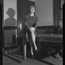 Shirley Ross, actress and singer, seated on a table in an office, 1933