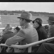 Actor Clark Gable and Ria Langham Gable in audience at outdoor event, 1930s
