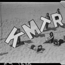 Young women on beach promoting radio station KMTR, Santa Monica, [1925-1946]