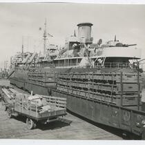Work trucks driving along docked boat, San Pedro Harbor, February 23, 1945
